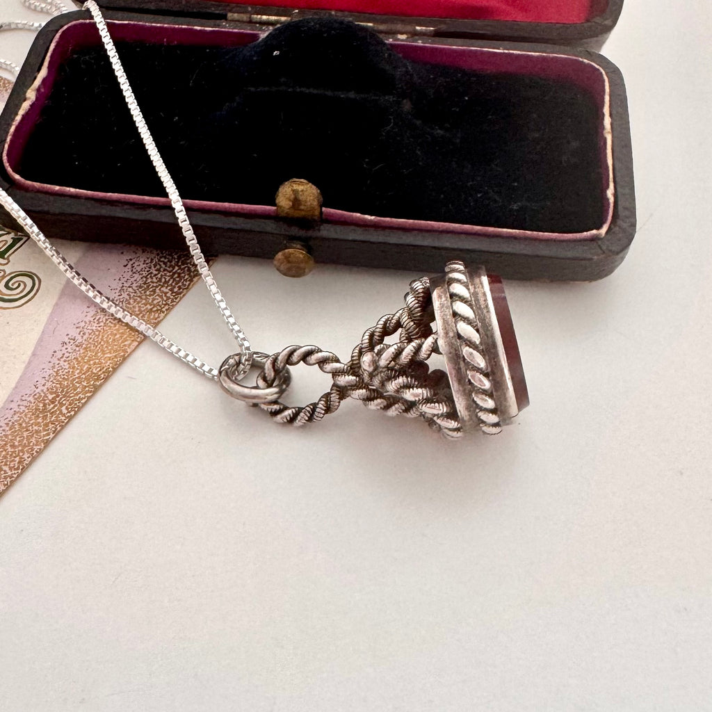 Antique silver and carnelian watch fob on a white background and with an old jewellery box