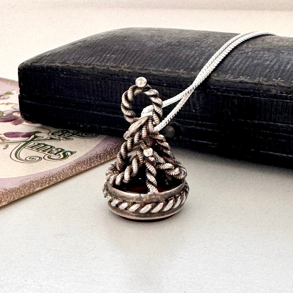 Antique silver and carnelian watch fob on a white background and with an old jewellery box