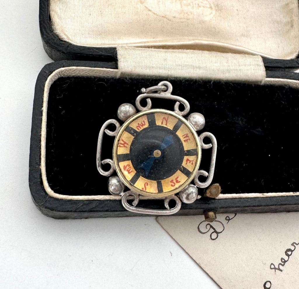 Decorative antique compass pendant with a circular design in a black case on a white background