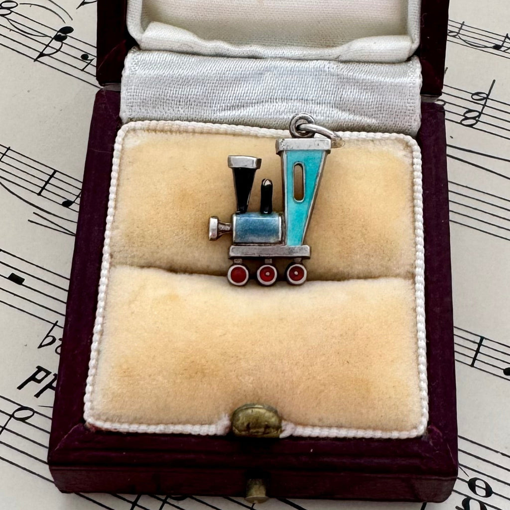 Antique silver and enamel Train-shaped charm in a jewelry box on sheet music