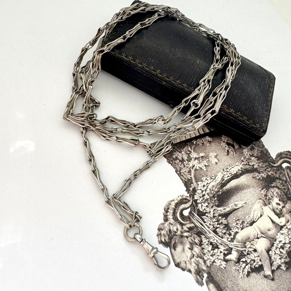 Antique silver fancy link guard chain on an old jewellery box and with an engraved picture in the corner