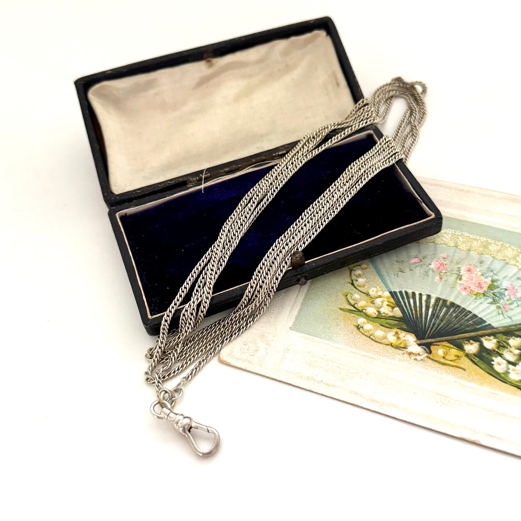 Antique silver guard chain necklace on a white background with an open jewelry box and a fan illustration.