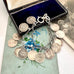 Silver coin bracelet with antique British threepence coins in an open jewelry box on a floral surface.