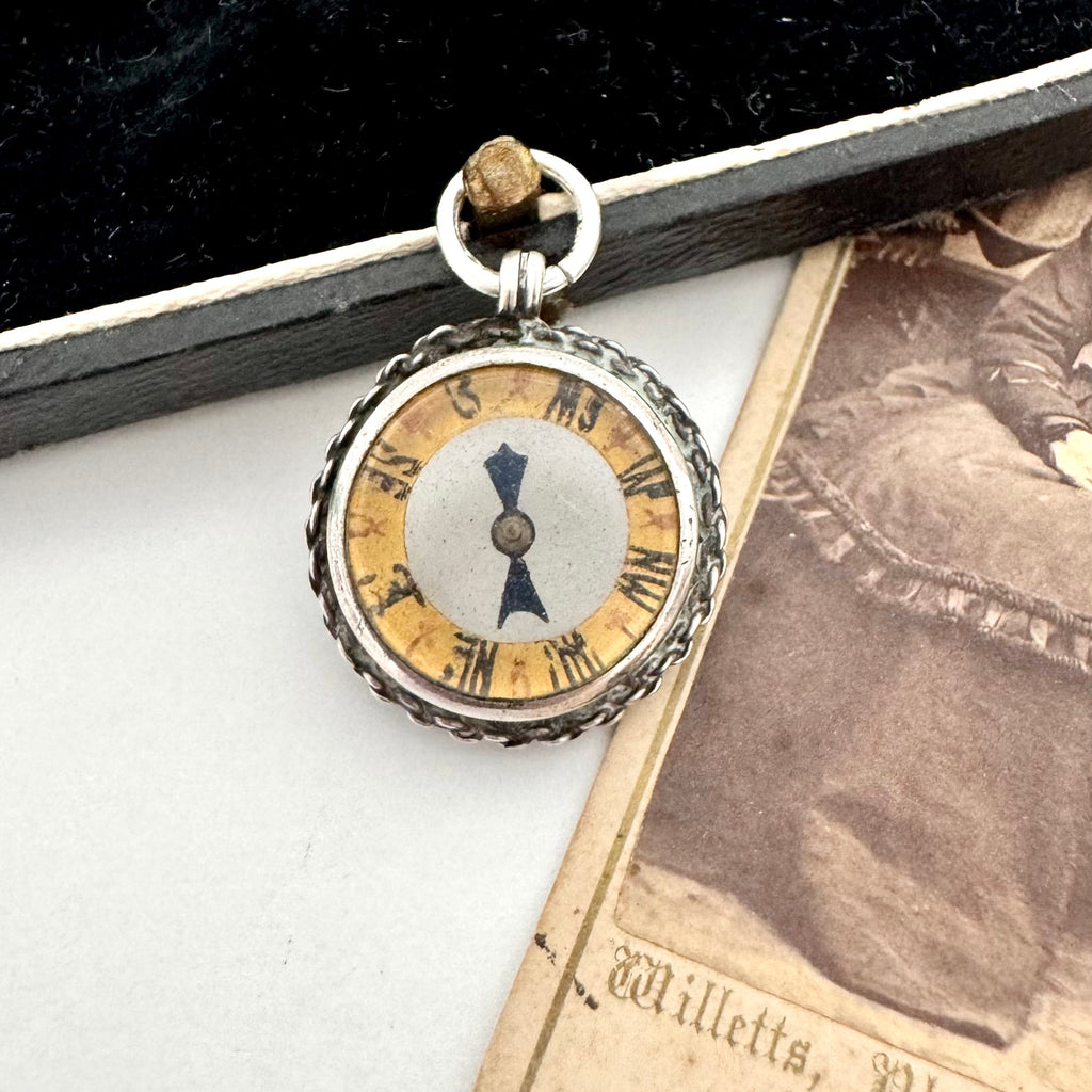 Antique silver compass watch fob on an old photograph