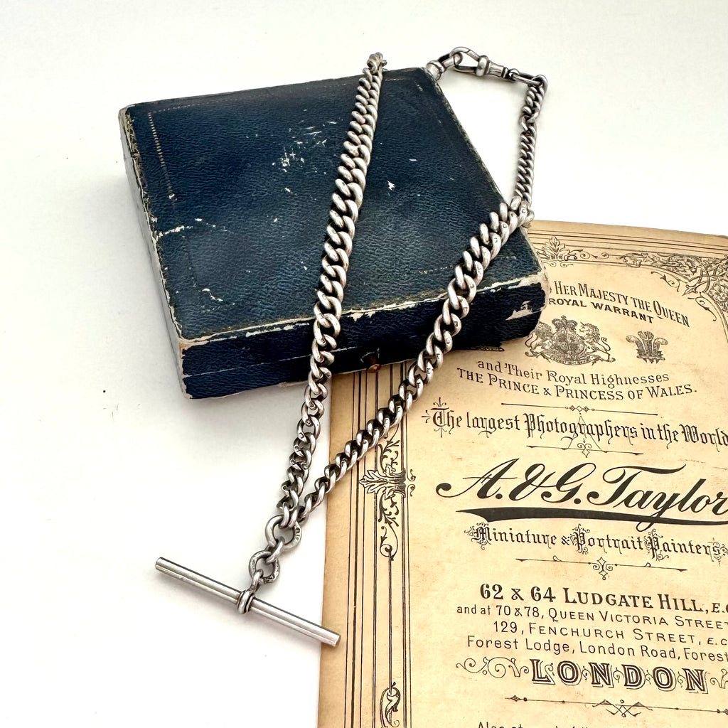 Antique sterling silver watch chain necklace on an old jewellery box and with some advertising material for a Victorian London Photographers studio.