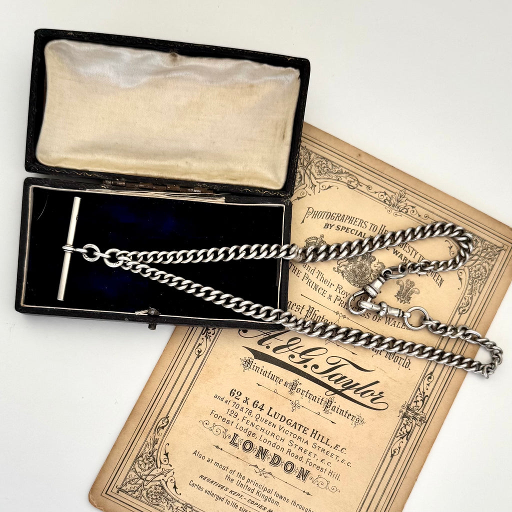 Antique sterling silver watch chain necklace on an old jewellery box and with some advertising material for a Victorian London Photographers studio.