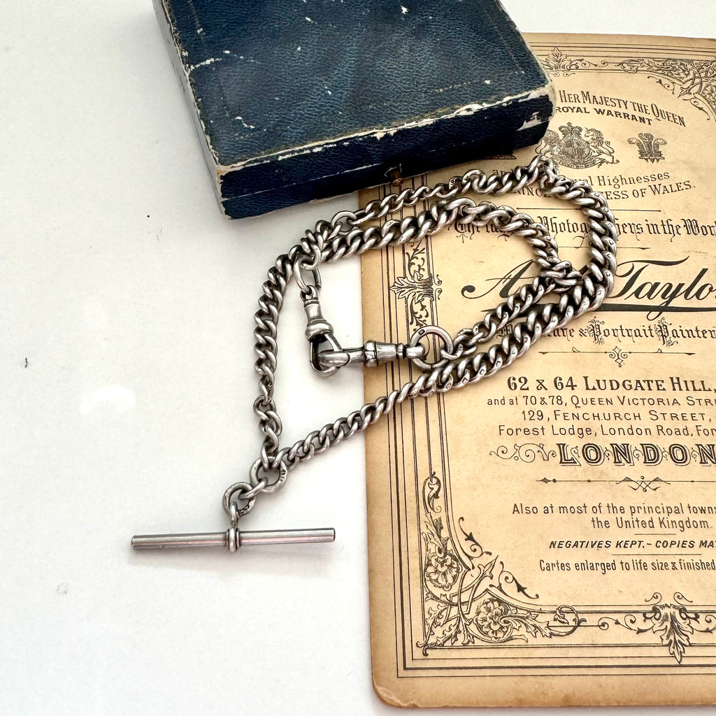 Antique sterling silver watch chain necklace on an old jewellery box and with some advertising material for a Victorian London Photographers studio.