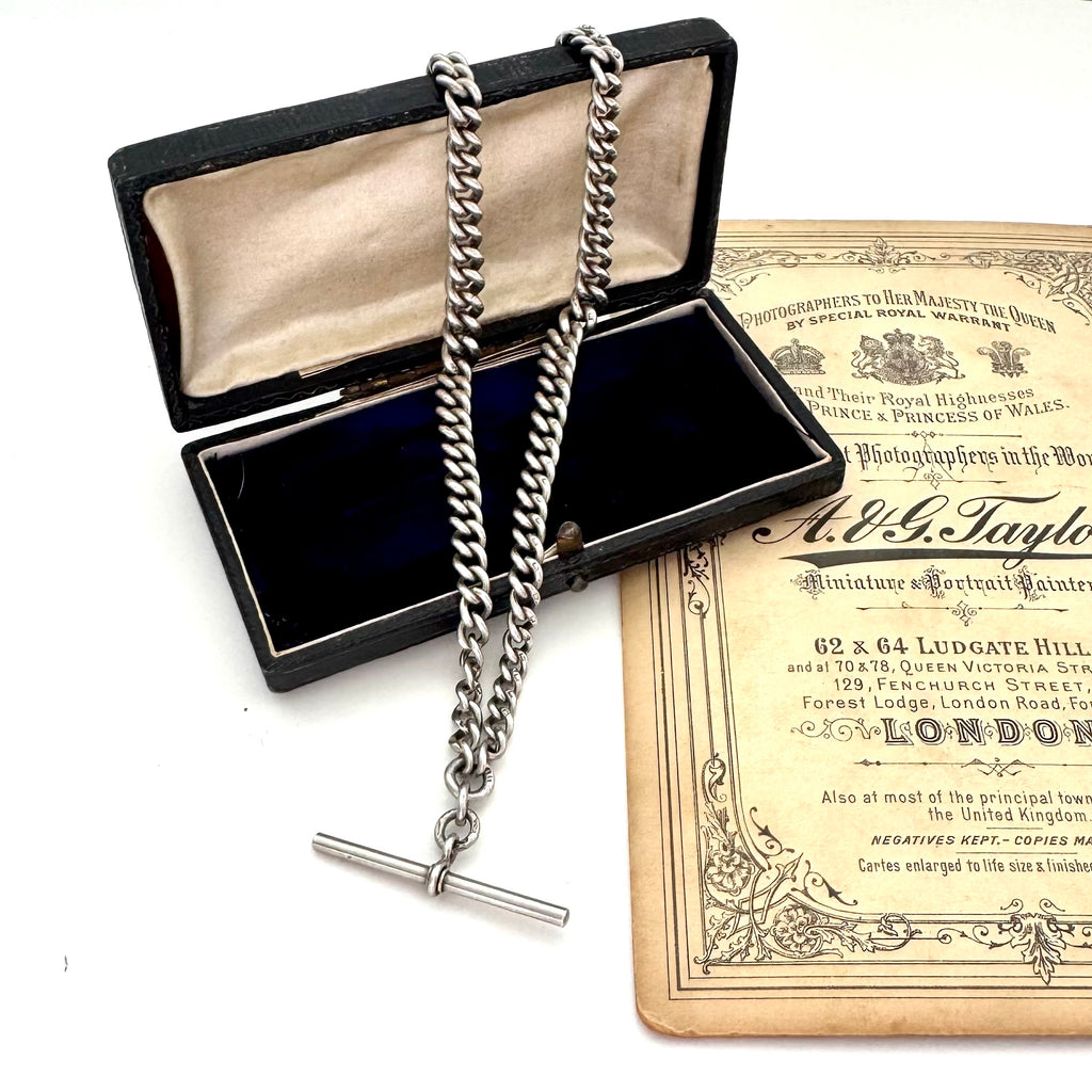 Antique sterling silver watch chain necklace on an old jewellery box and with some advertising material for a Victorian London Photographers studio.