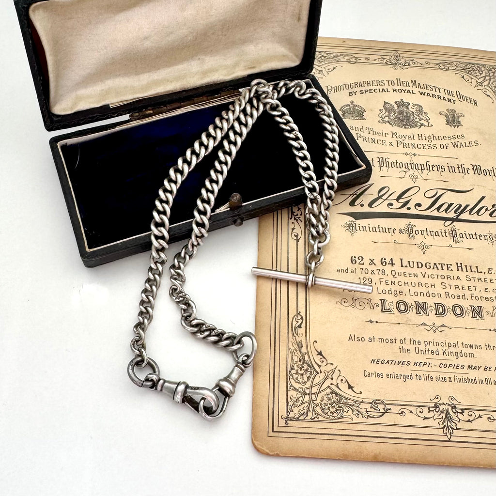 Antique sterling silver watch chain necklace on an old jewellery box and with some advertising material for a Victorian London Photographers studio.