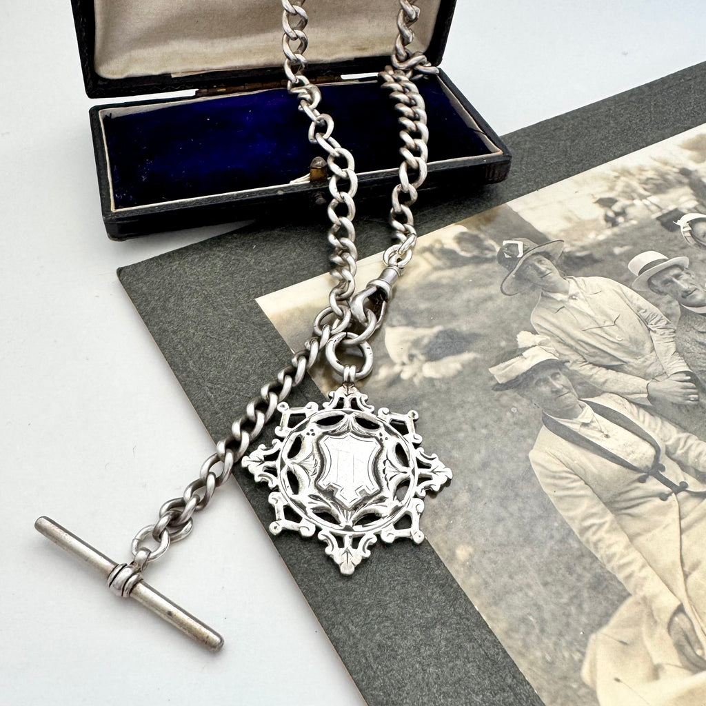 Antique silver albert watch chain and watch fob necklace with an albert clasp on a vintage-style card and jewellery box.