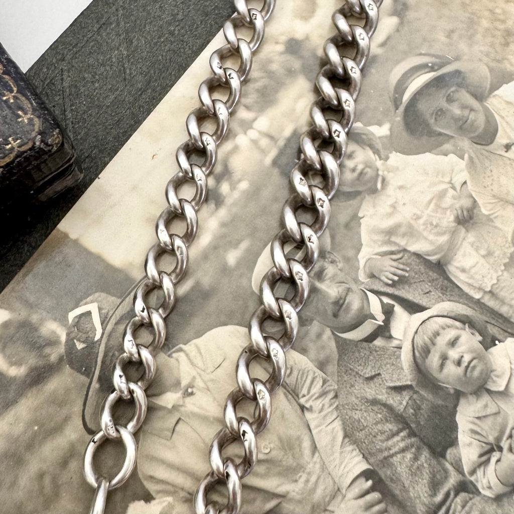Silver chain over an old photograph of people and a corner of a jewellery box