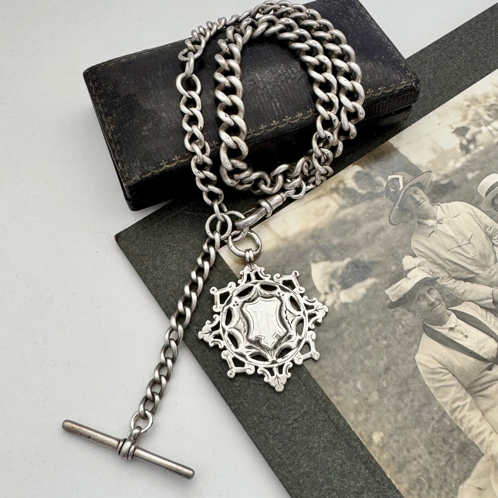 Antique silver albert watch chain and watch fob necklace with an albert clasp on a vintage-style card and jewellery box.
