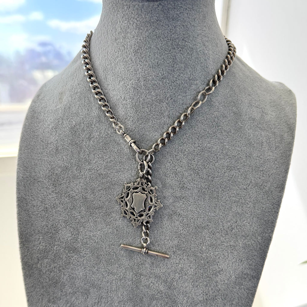 Antique silver albert watch chain and watch fob necklace with an albert clasp on a grey mannequin.