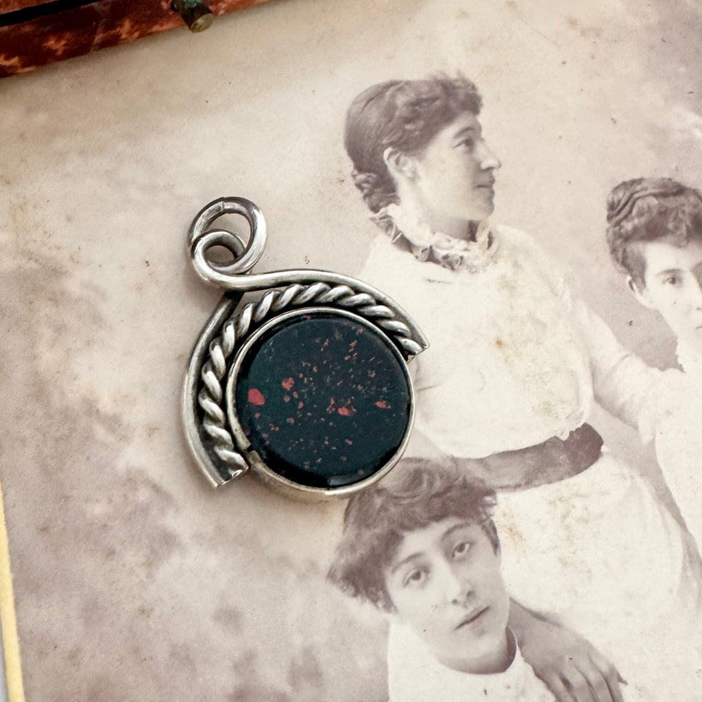 Antique victorian albo silver carnelian and bloodstone spinning fob displayed on top of a vintage sepia-toned photograph.