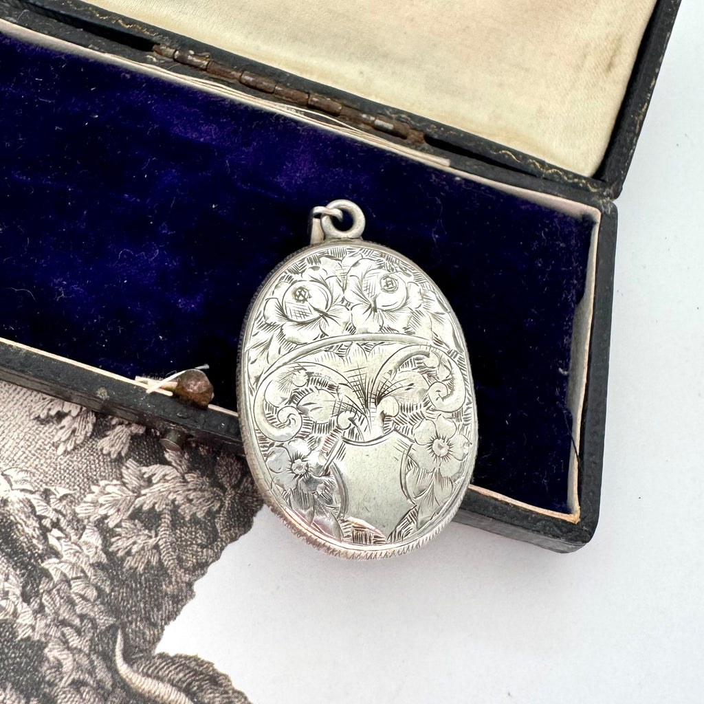 Antique Victorian era silver locket with an engraving of an urn and an old jewellery box