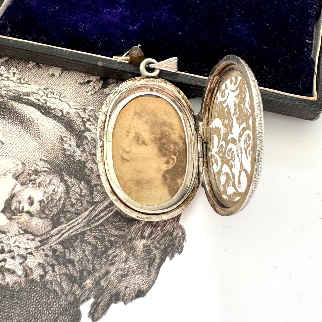 Inside an antique Victorian era silver locket with an engraving of an urn and an old jewellery box