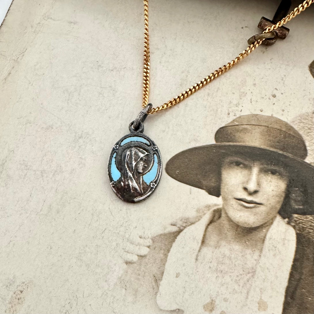 An antique religious charm on an old photo of a woman wearing a hat