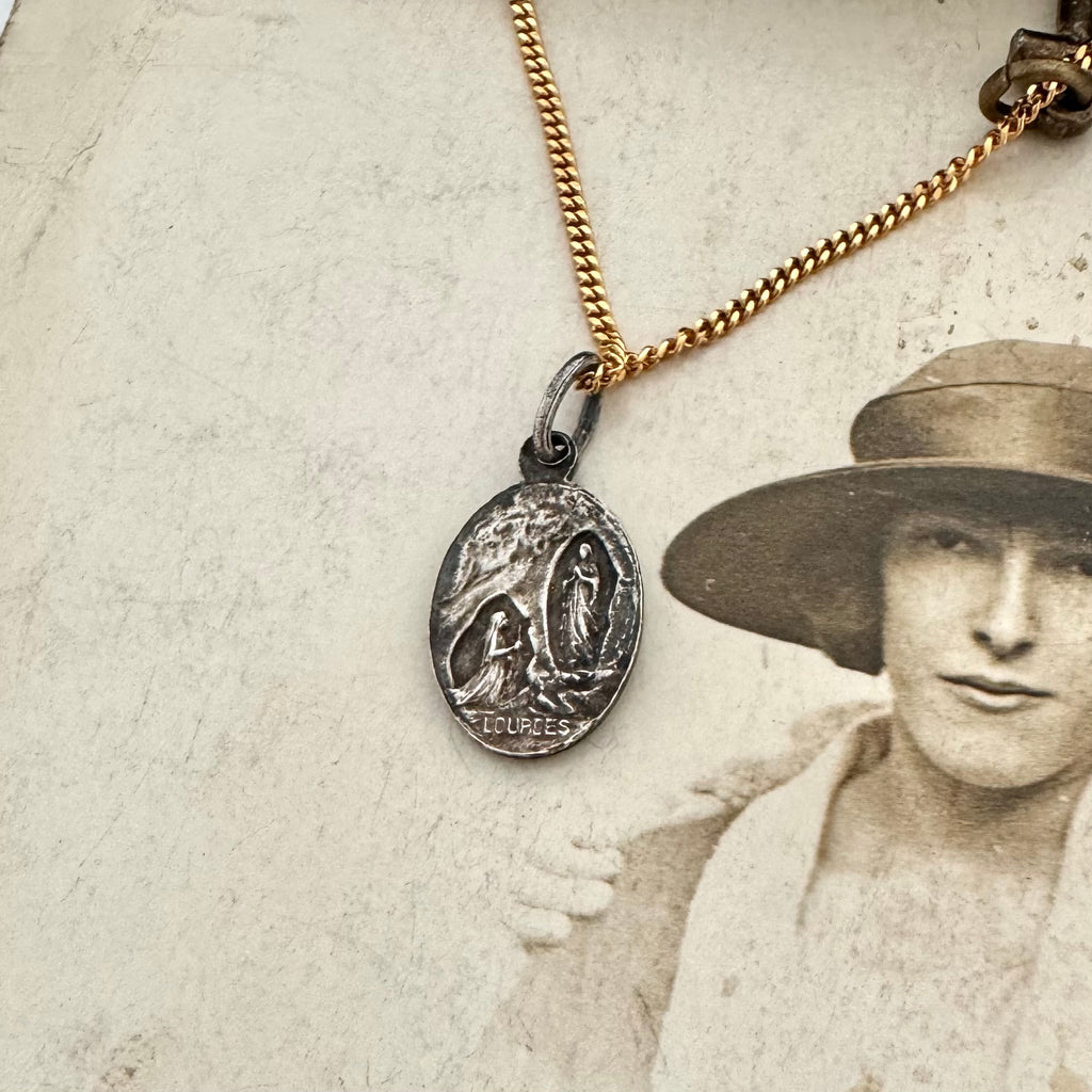 An antique religious charm on an old photo of a woman wearing a hat
