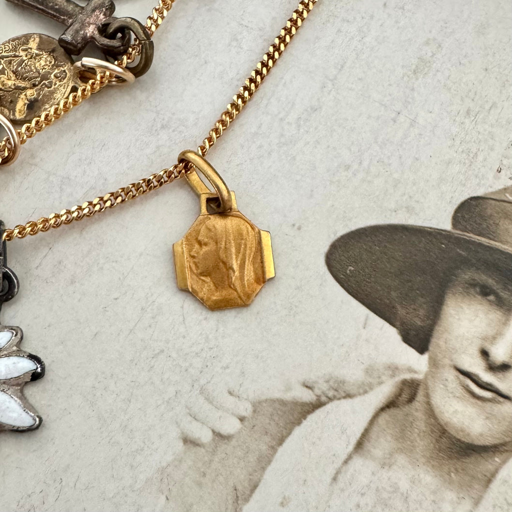 An antique religious charm on an old photo of a woman wearing a hat