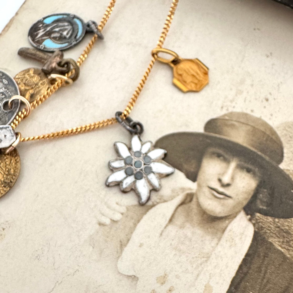 A vintage eidleweiss charm on an old photo of a woman wearing a hat