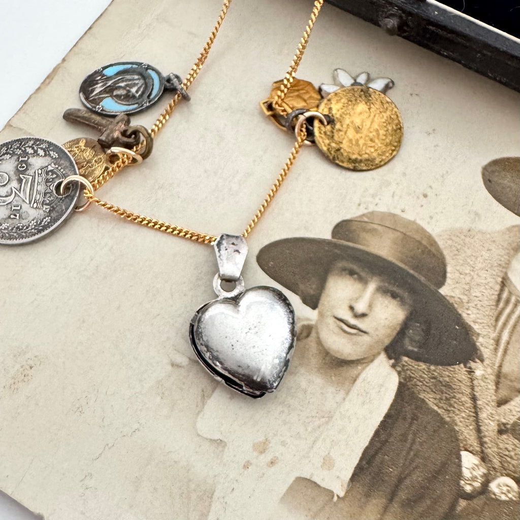 An antique heart charm on an old photo of a woman wearing a hat