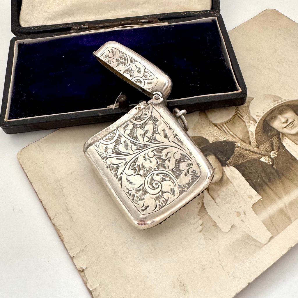 Antique 1911 William Hair Haseler silver vesta case with intricate designs on a vintage photo and box
