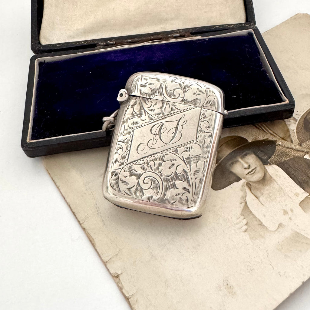 Antique 1911 William Hair Haseler silver vesta case with intricate designs on a vintage photo and box