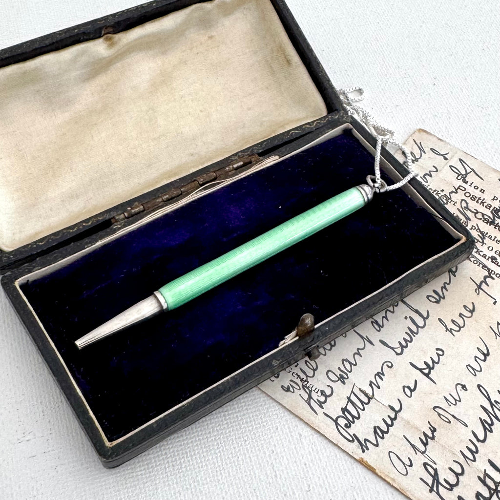 Art Deco silver and guilloche enamel propelling pencil, displayed inside an open vintage black presentation box with a dark blue velvet lining, next to an antique handwritten letter.
