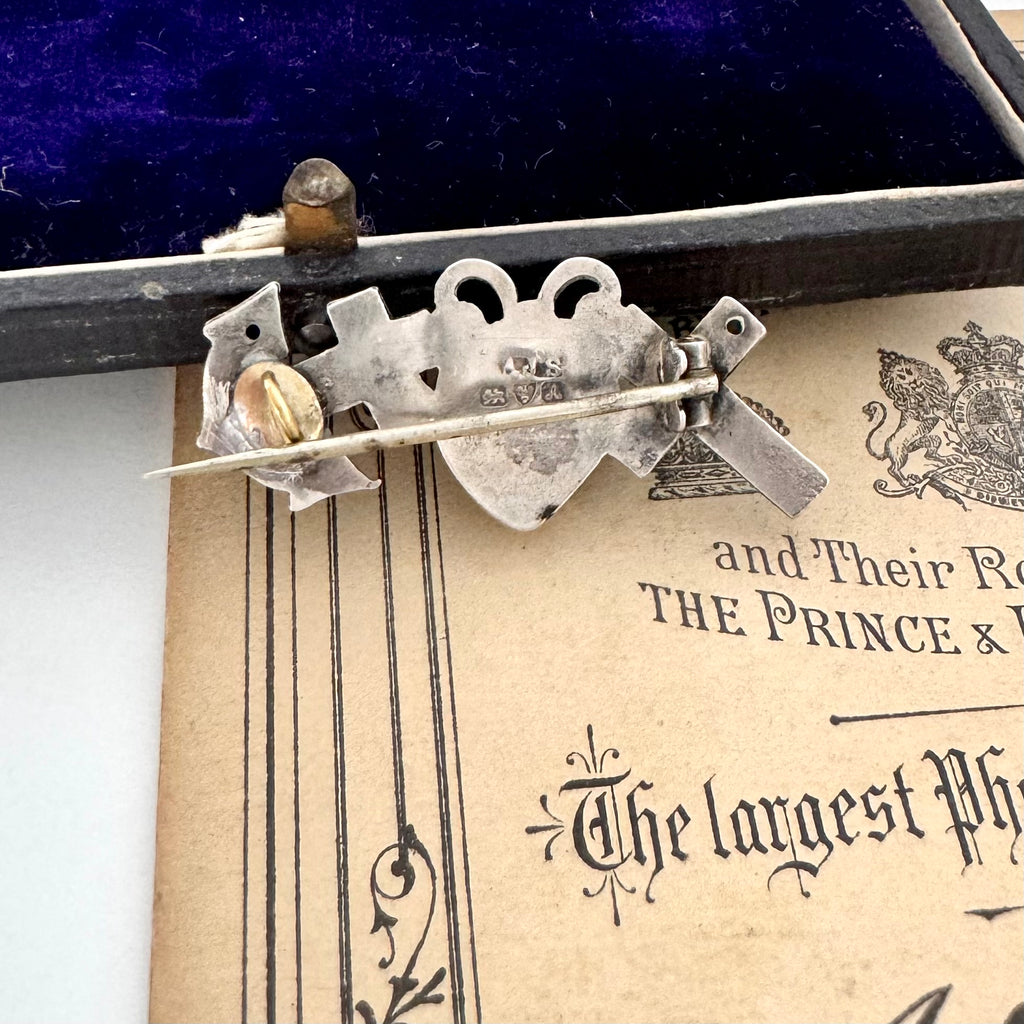 Antique 1901 faith, hope and charity brooch on a vintage jewellery box.