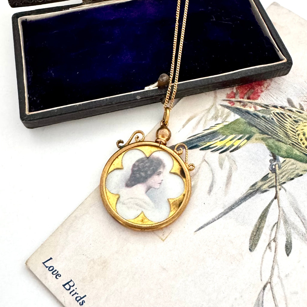 Vintage-style necklace with a pendant featuring a woman's portrait on a decorative surface.