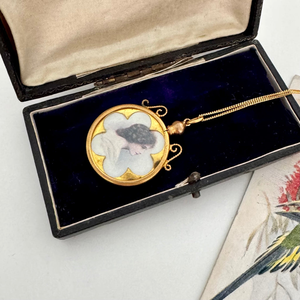 Vintage locket with floral design in a black box on a white surface