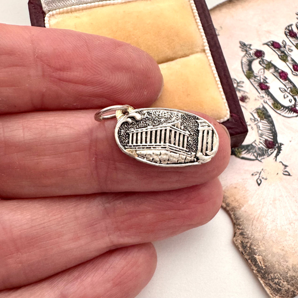 Silver pendant on a finger with a decorative background