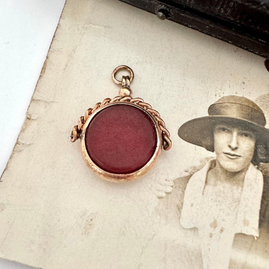 Antique rolled gold carnelian and bloodstone spinning fob on an antique photo of a woman and with a vintage jewellery box in the corner.