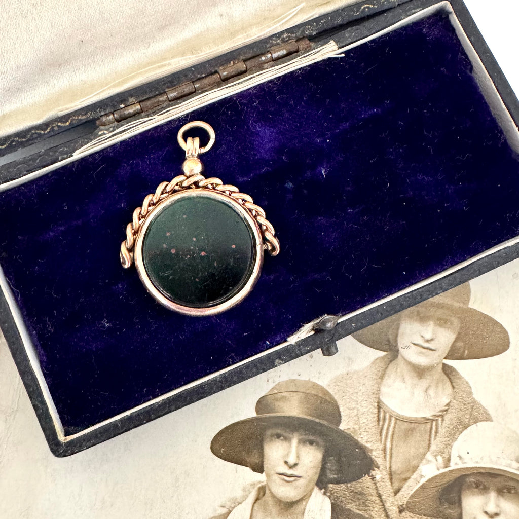 Antique rolled gold carnelian and bloodstone spinning fob on a vintage jewellery box and with an antique photo.