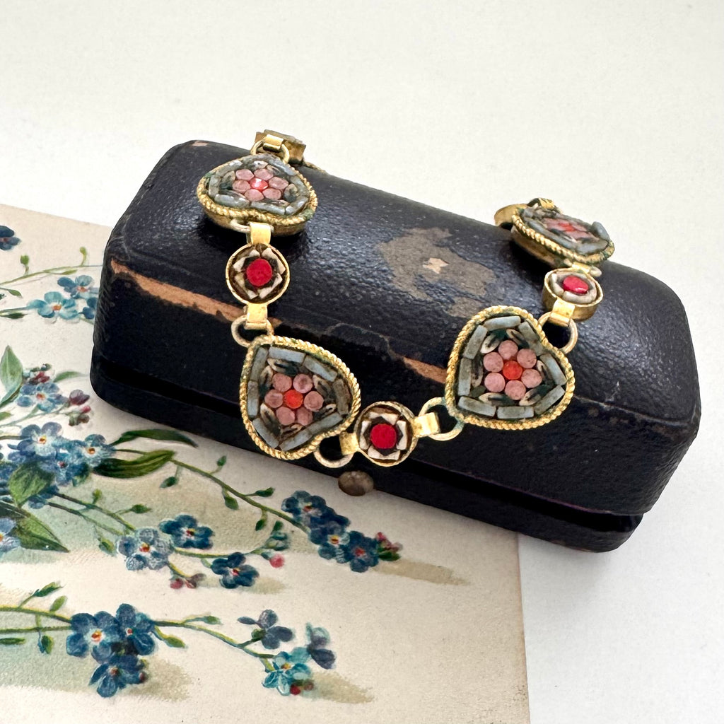 Vintage micro mosaic bracelet with floral designs in a jewelry box on a floral vintage postcard.