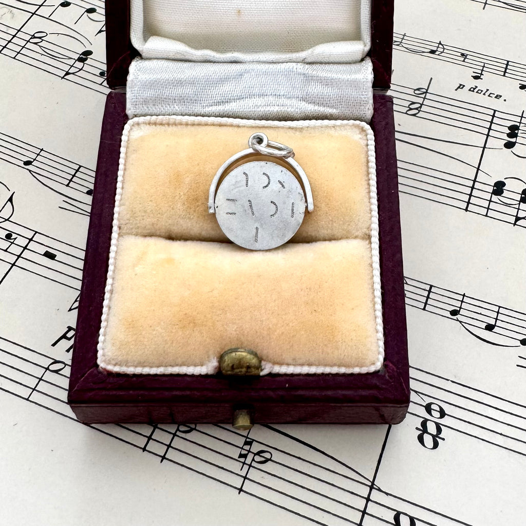 Silver vintage spinning I Love You charm in a jewelry box on sheet music
