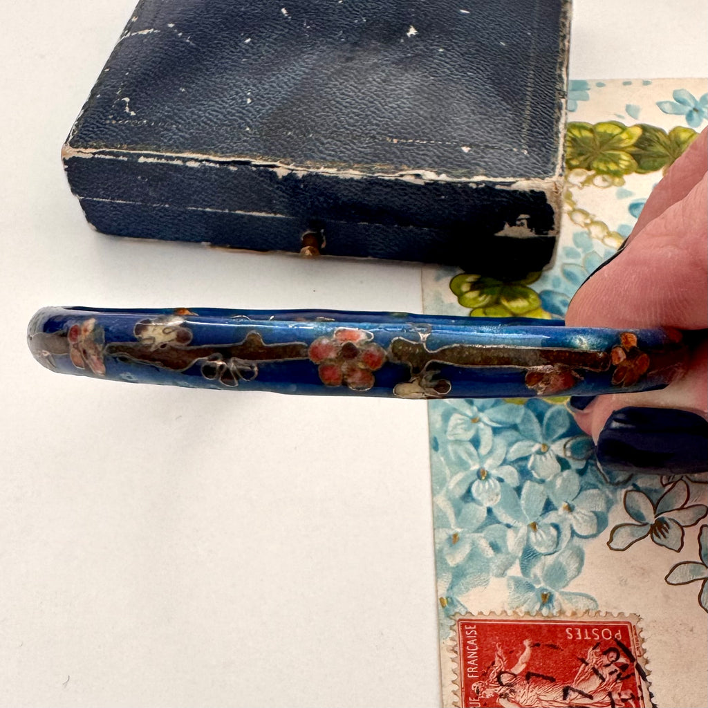 Vintage blue cloisonne bangle in a woman's hand and with on an old jewellery box and vintage postcard