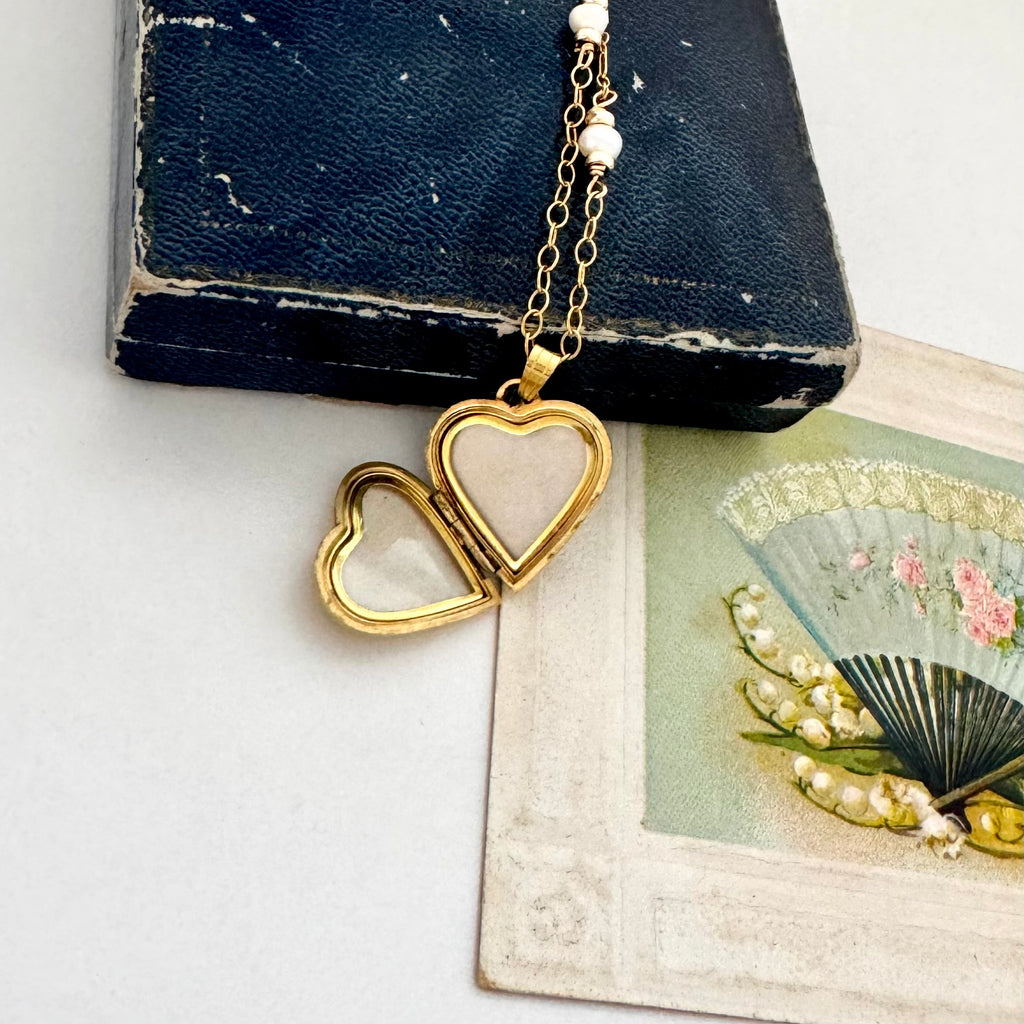 gold locket heart pendant on an old book and card background