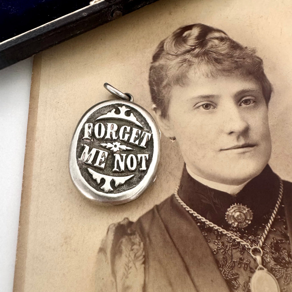Victorian silver plated Forget Me Not locket on a Victorian photograph of a woman wearing a brooch and a locket.