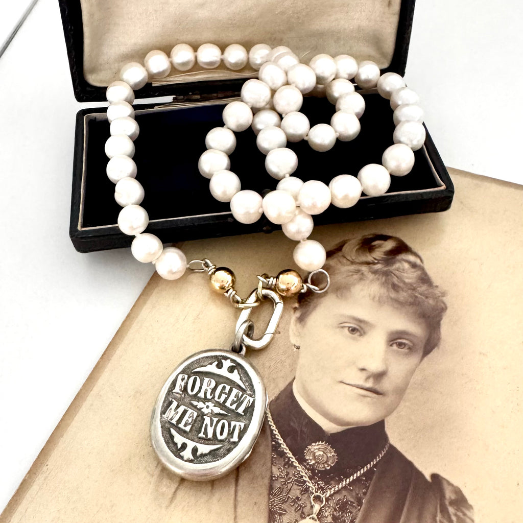 Victorian silver plated Forget Me Not locket on a Victorian photograph of a woman wearing a brooch and a locket. The locket is on a Vonk Jewellery pearl necklace.