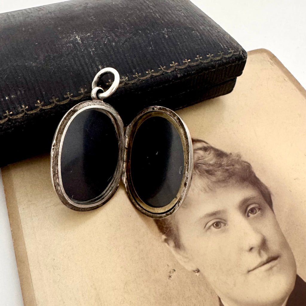 Victorian silver plated Forget Me Not locket on a Victorian photograph of a woman wearing a brooch and a locket. The locket is open showing the inserts for 2 photogrpahs
