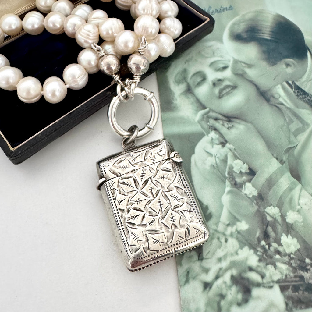 Vonk Jewellery antique sterling silver vesta case on a pearl necklace. The necklace is on a vintage green French postcard and a vintage jewellery box.