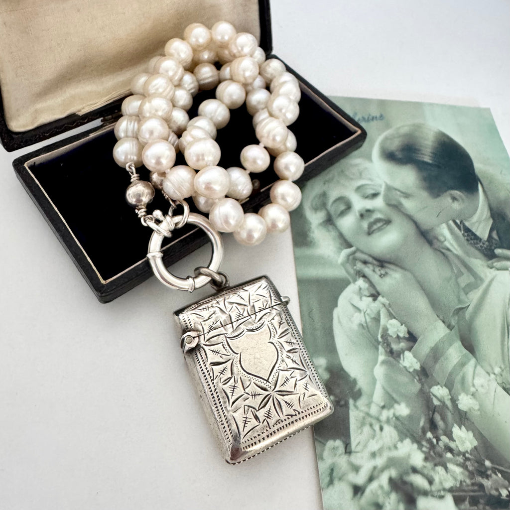 Vonk Jewellery antique sterling silver vesta case on a pearl necklace. The necklace is on a vintage green French postcard and a vintage jewellery box.