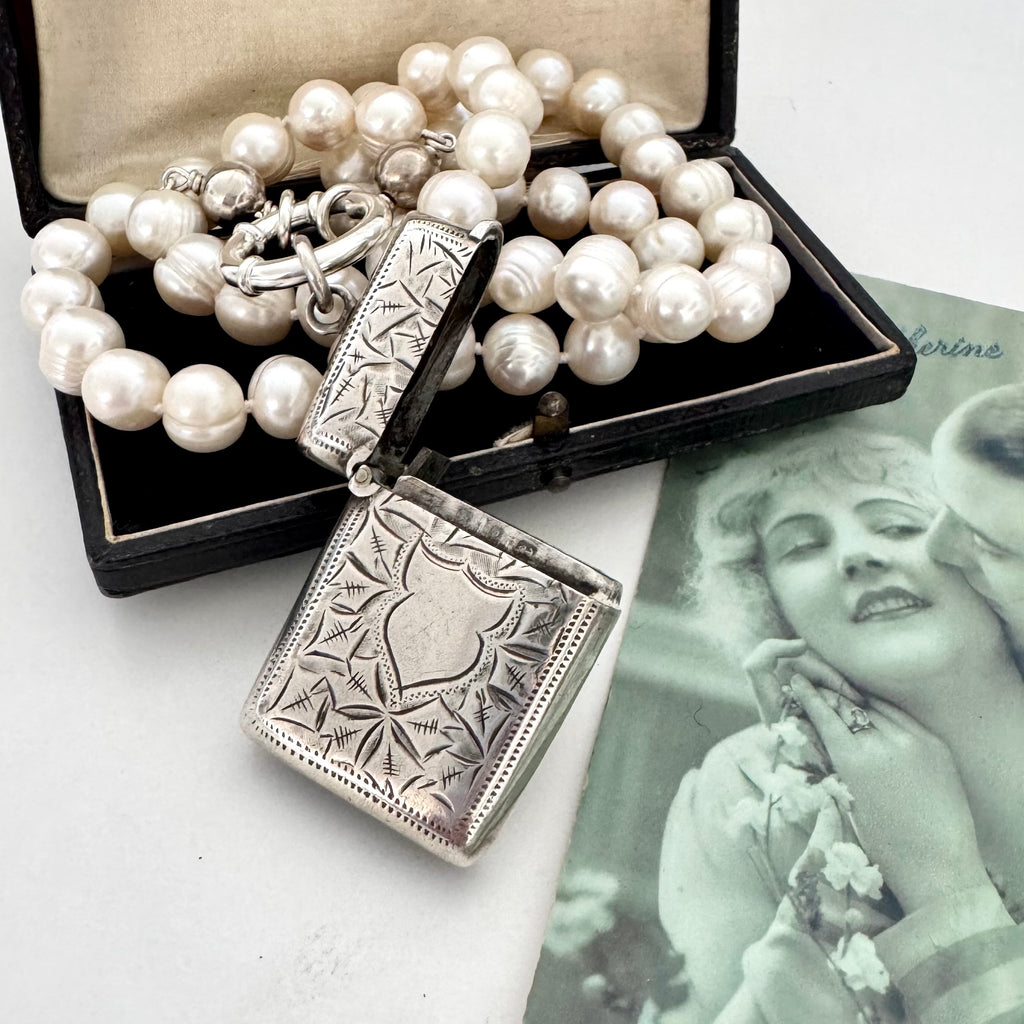 Vonk Jewellery antique sterling silver vesta case on a pearl necklace. The necklace is on a vintage green French postcard and a vintage jewellery box.