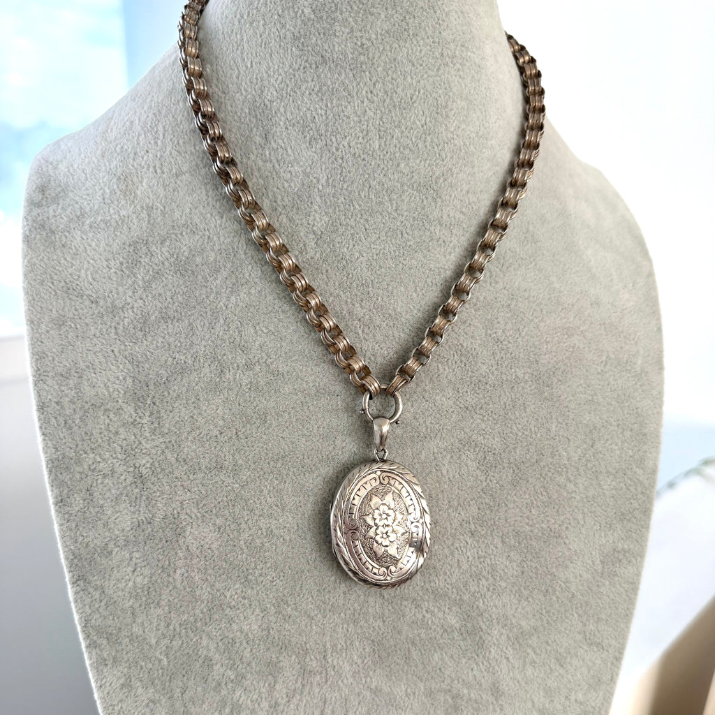 Silver Victorian chain and locket on a mannequin bust against a light background