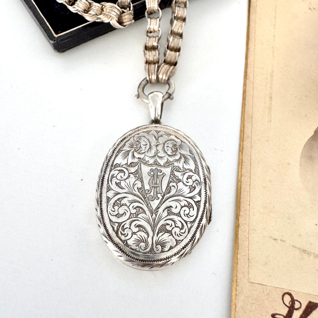 Victorian silver locket with intricate designs on a white surface