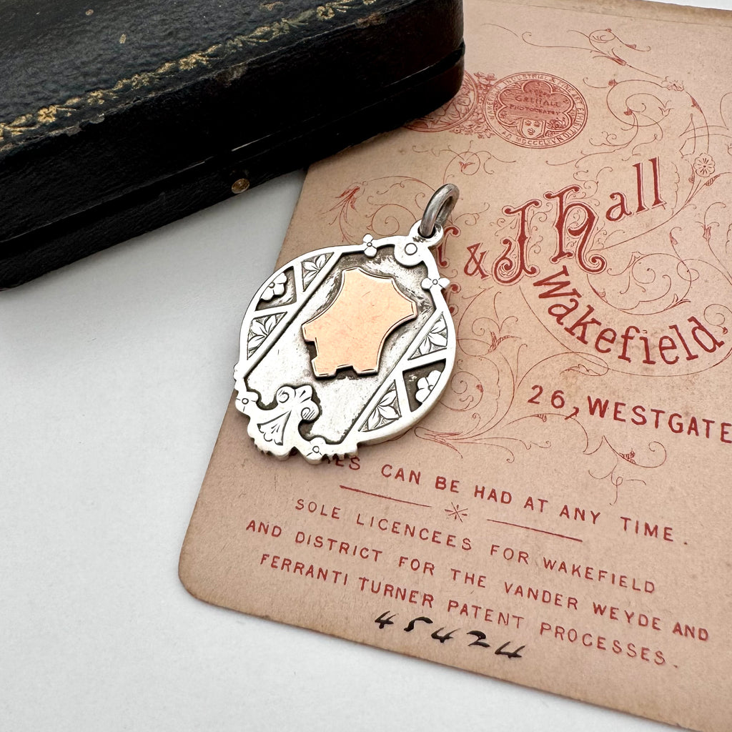 Vintage watch fob pendant with a rose gold cartouche on a vintage-style card