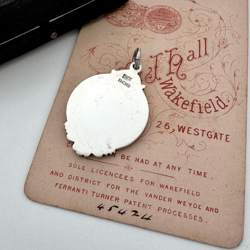 Back of vintage watch fob pendant with a rose gold cartouche on a vintage-style card