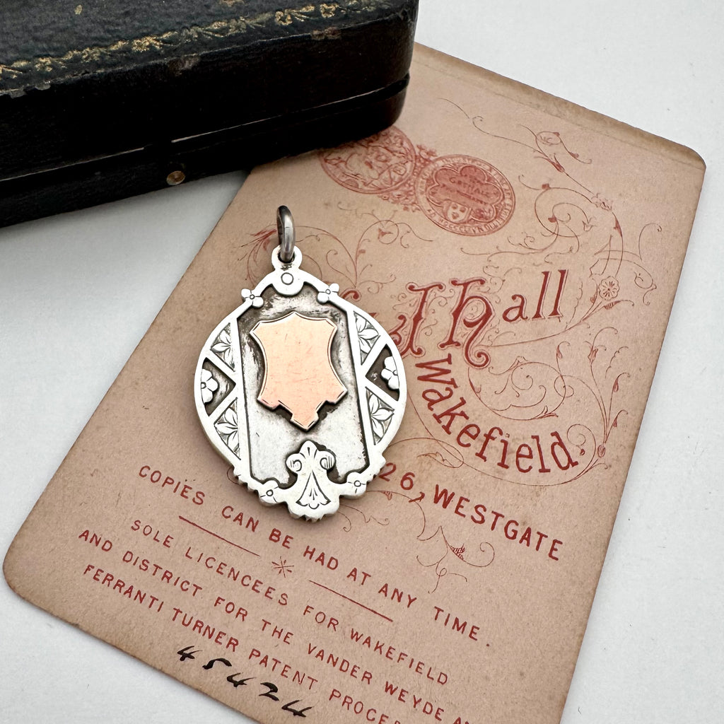 Vintage watch fob pendant with a rose gold cartouche on a vintage-style card