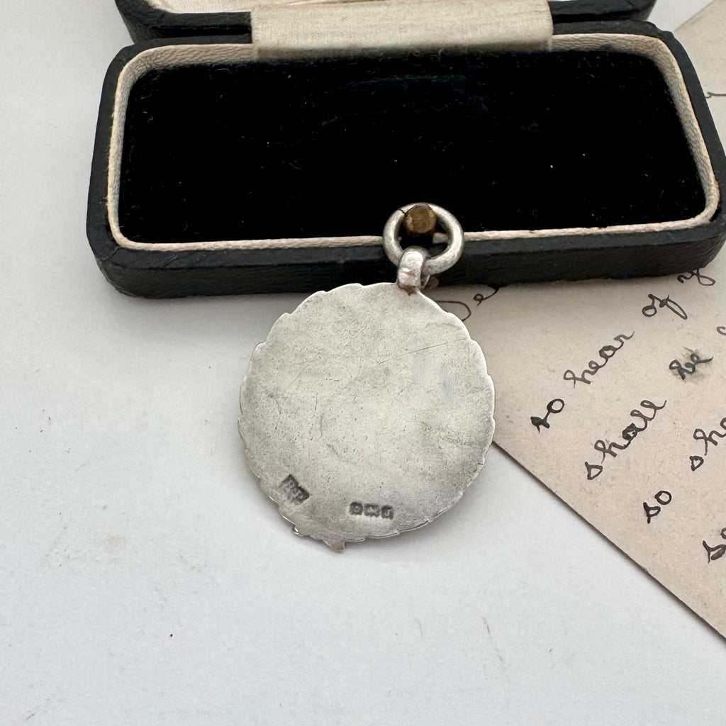 Vintage silver watch fob on a white surface